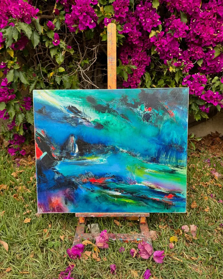 Tableau abstrait turquoise et bleu de Régine Gardan, touches rouges, sur un chevalet sous des bougainvilliers roses