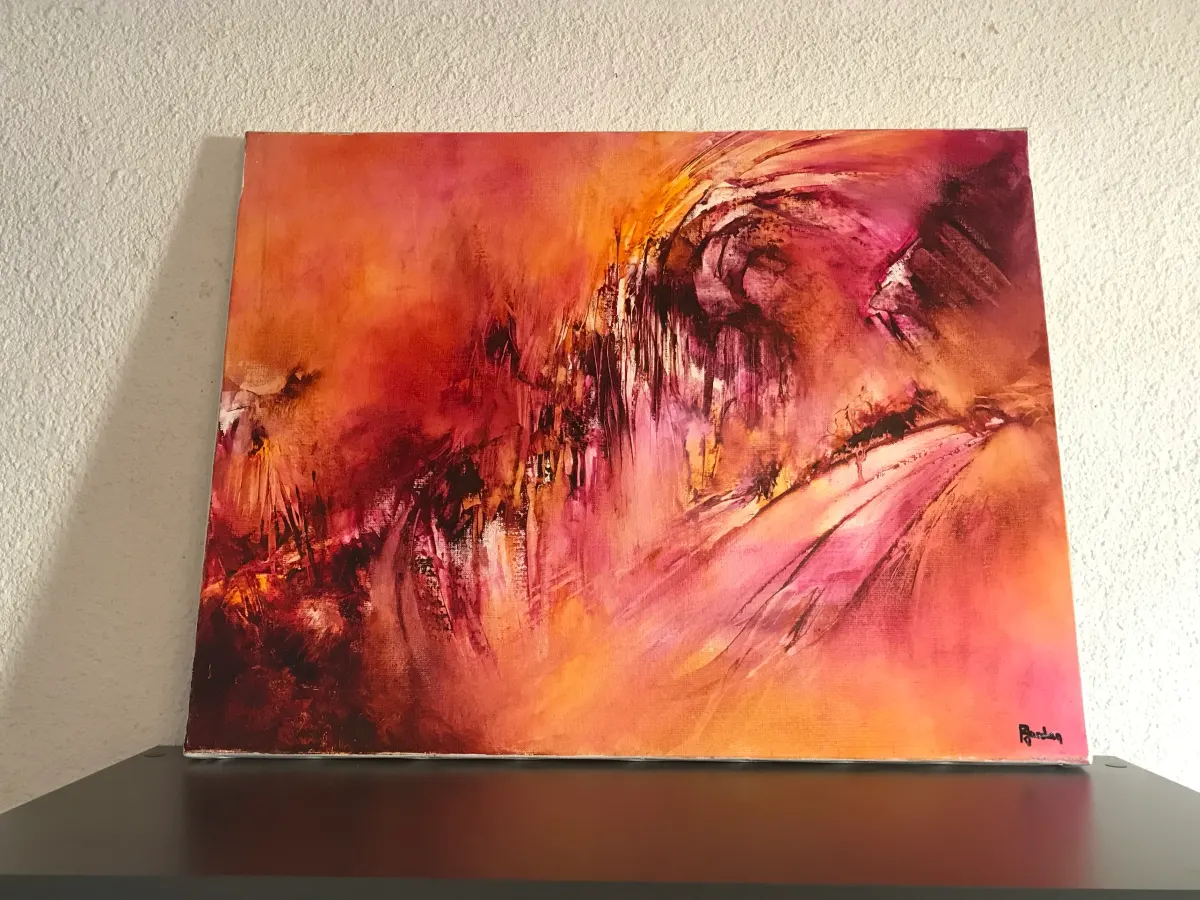 Tableau abstrait orange et rose de Régine Gardan posé sur un meuble, chez Lucas