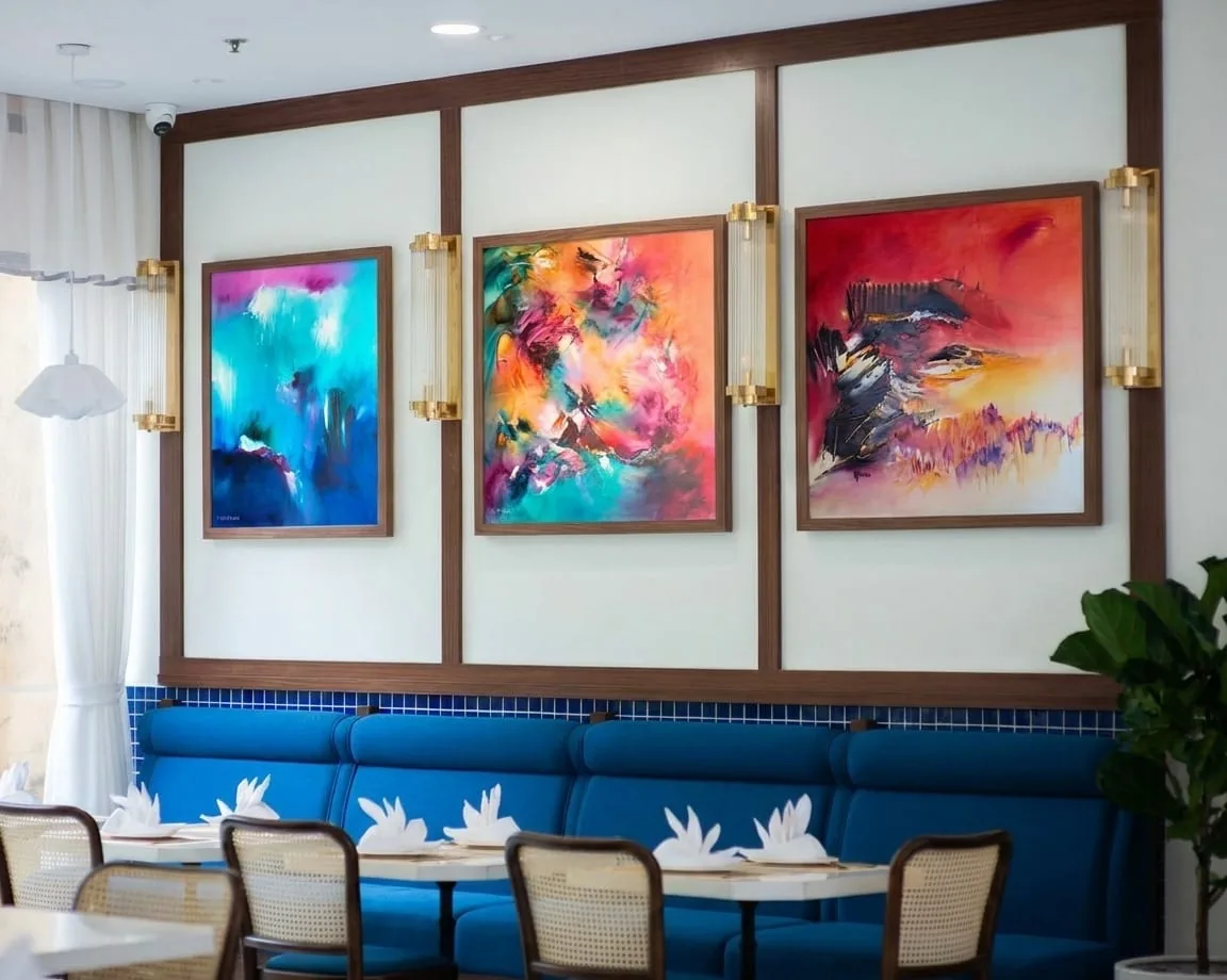 Mise en situation : trois toiles abstraites de Régine Gardan dans une salle de restaurant moderne