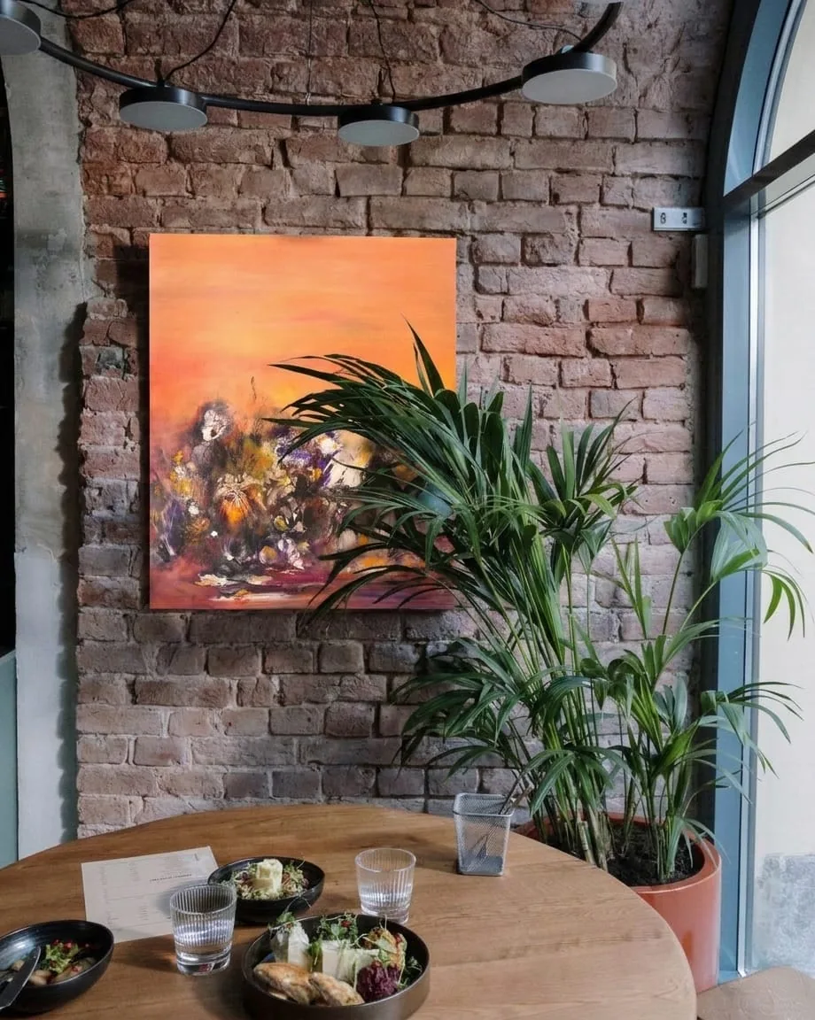 Mise en situation : la toile abstraite Uluru de Régine Gardan sur le mur en brique d'un café restaurant