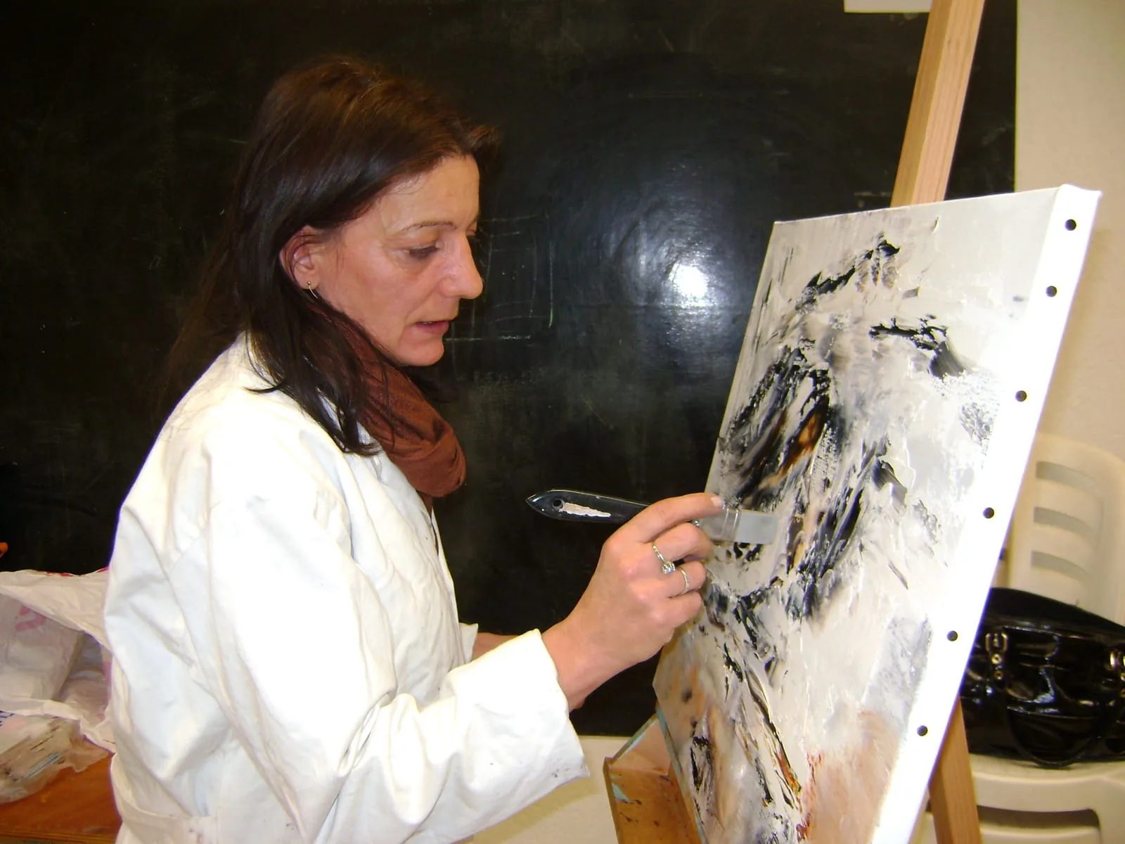 Régine Gardan travaillant une toile abstraite au couteau dans son atelier